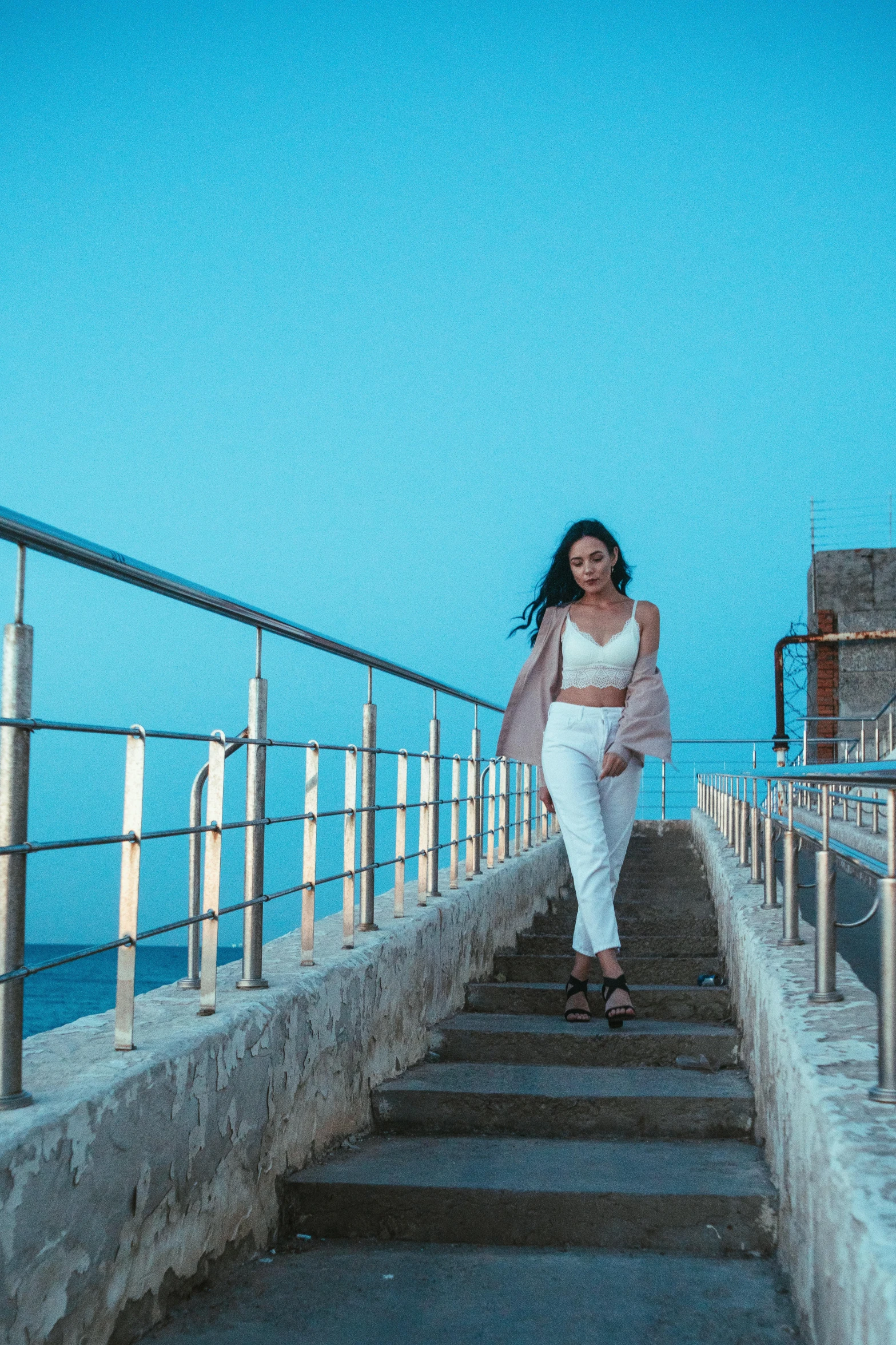 a woman is walking up some steps near the ocean