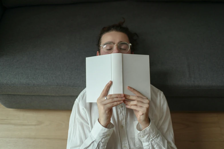 a woman with eyeglasses on lying on the floor reading a book