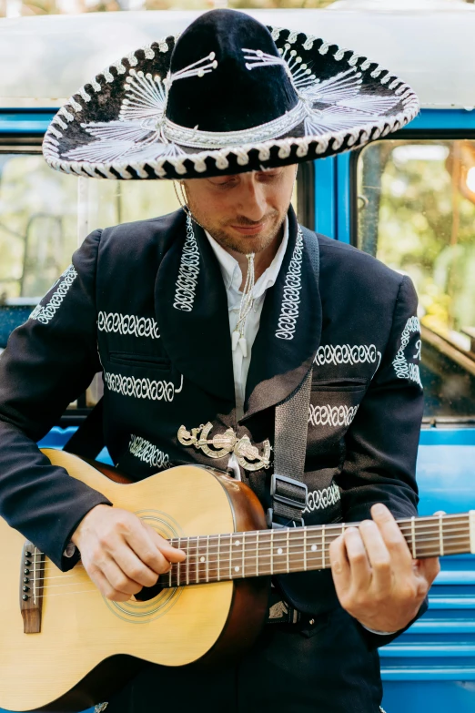 a mexican man holding a guitar in front of a blue truck