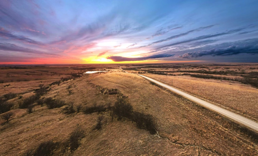 a sunset on an empty dirt road in the middle of nowhere