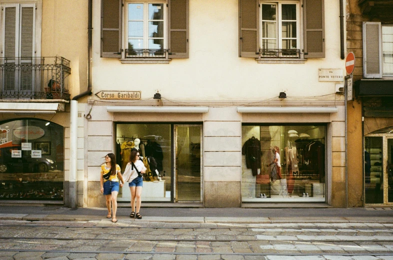 two women walking past an store front on the sidewalk