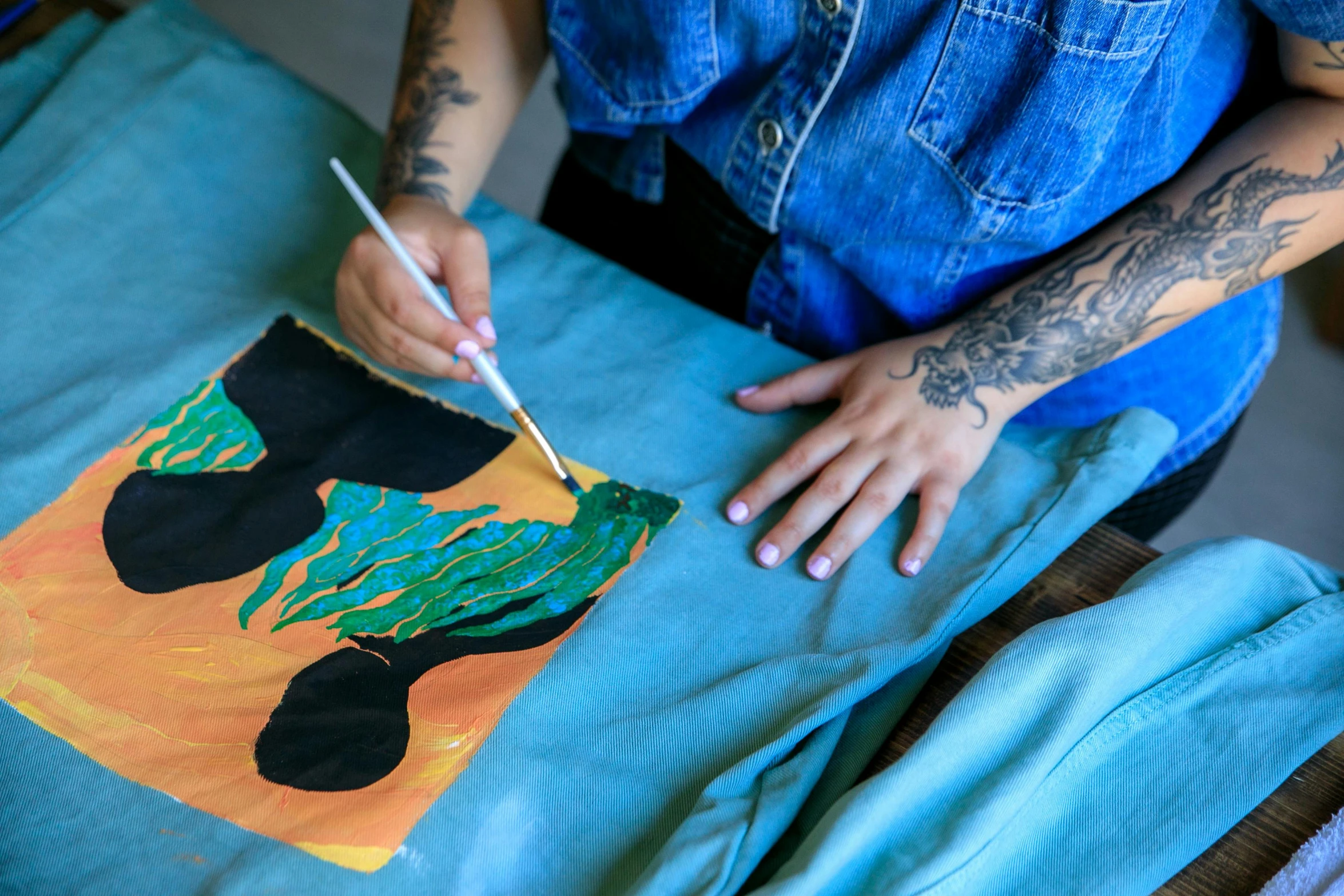 a person holds a small item with their hands as she attempts to paint a bear on a canvas