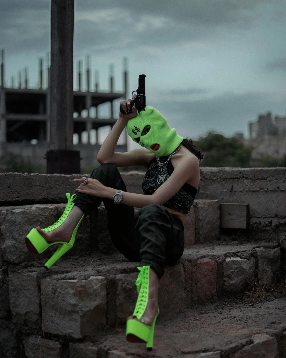 woman with neon green mask holding up a gun