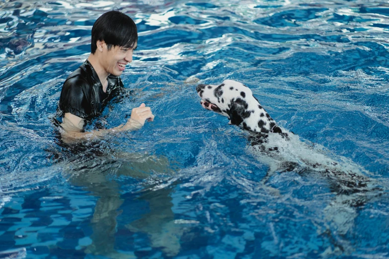 a young man and a dalmation swimming in a pool