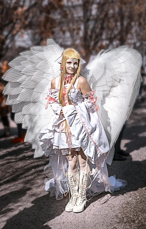 an angel with large wings is posing in a park