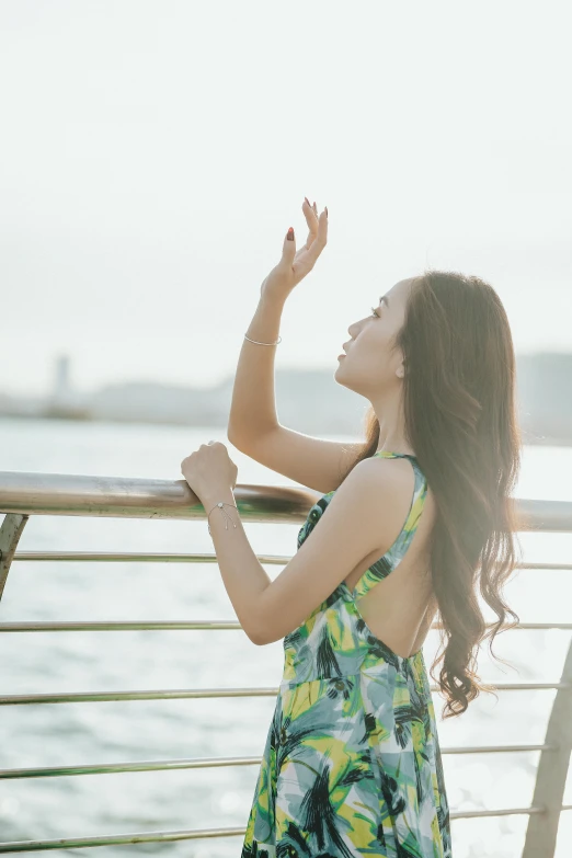 a woman stands by the water with her arms outstretched