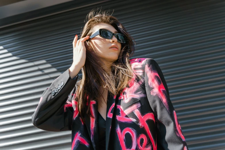 a woman standing in front of a building with a black and pink jacket