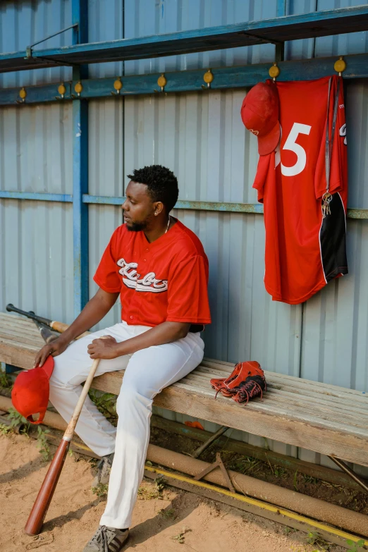 a baseball player is sitting on the bench holding a bat