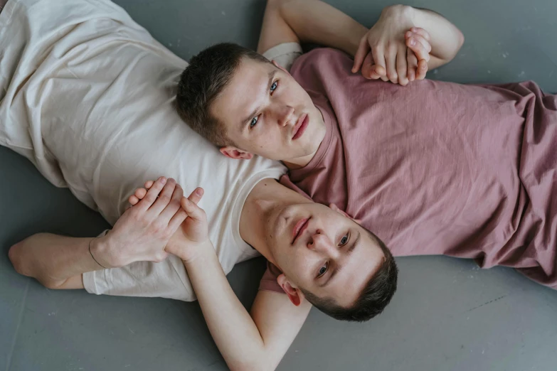 two young men lying on the ground next to each other