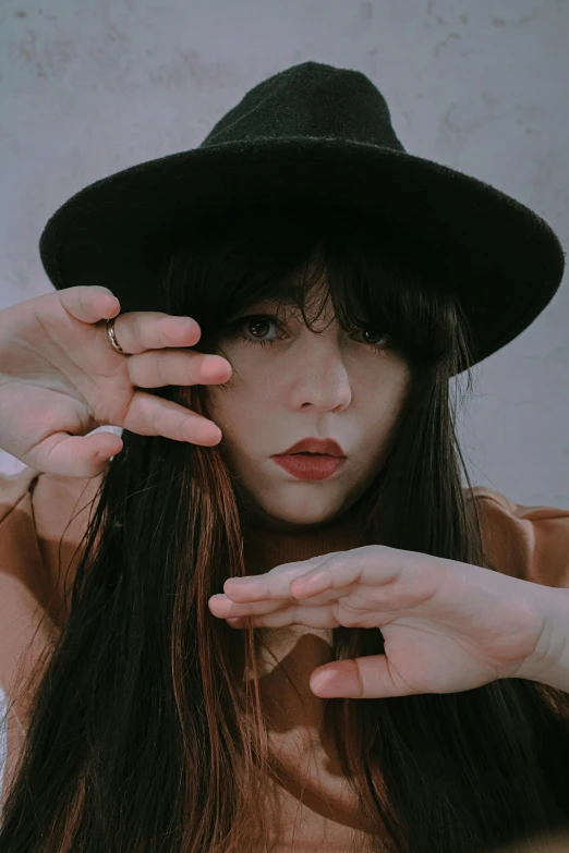 a woman putting on a black hat in her hands