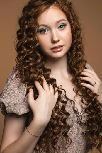 a woman with curly red hair standing next to a brown wall