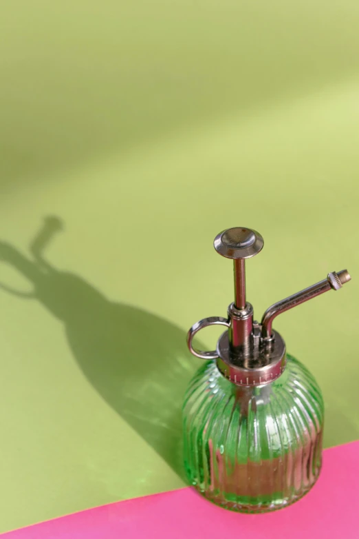 a green glass oil dispenser sitting on a pink and yellow table