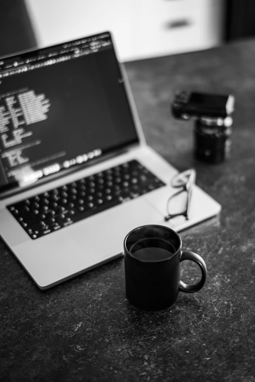 a black and white po of a laptop and a mug