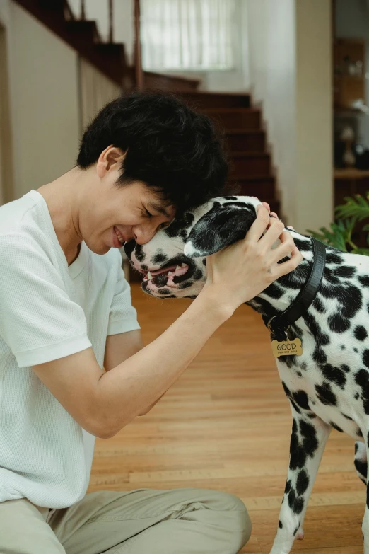 man hugging his dalmation dog on the floor