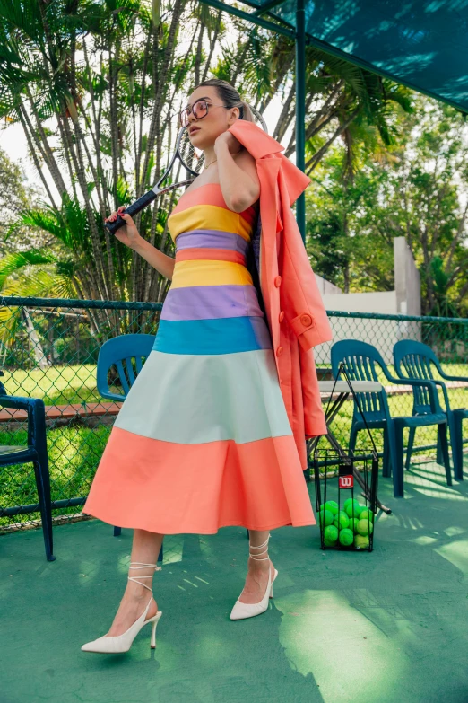 a woman in a rainbow striped dress holding an umbrella