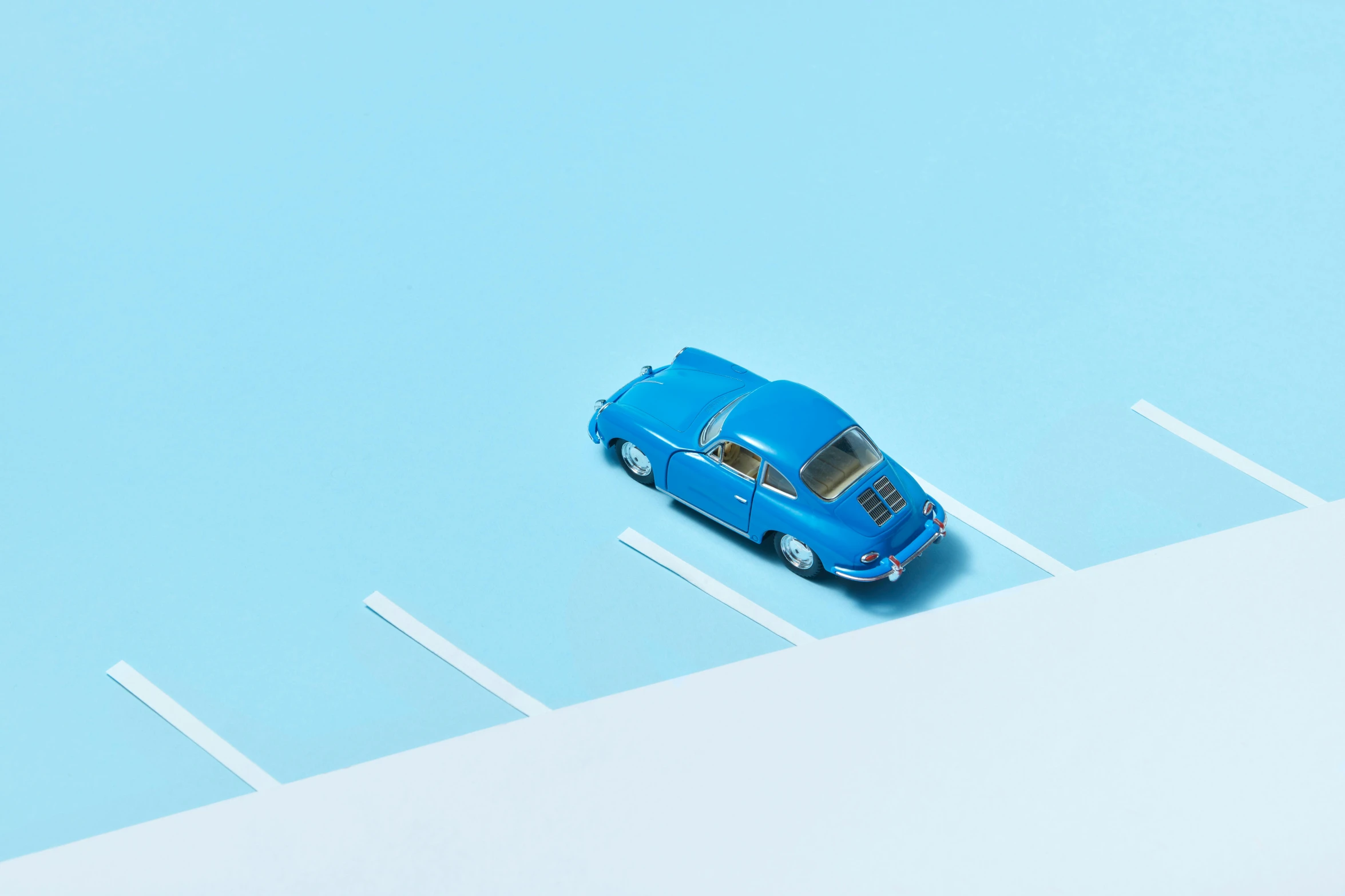 blue toy car parked on a strip of white concrete