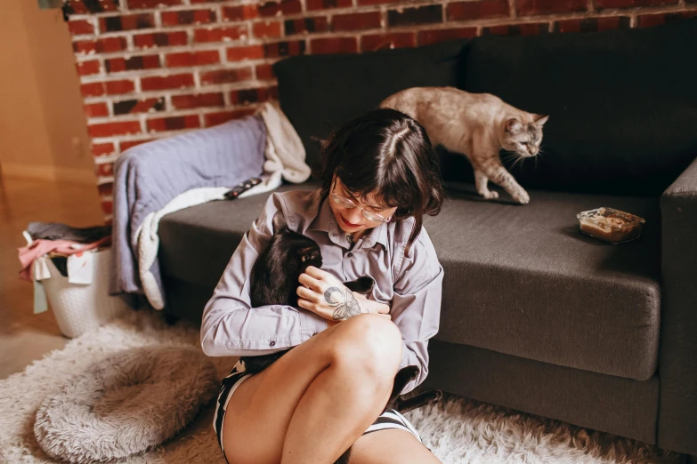 a woman sitting on the floor playing with her cat