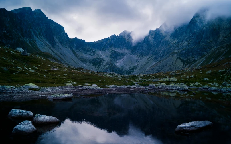 mountains are covered with low cloud cover over a lake