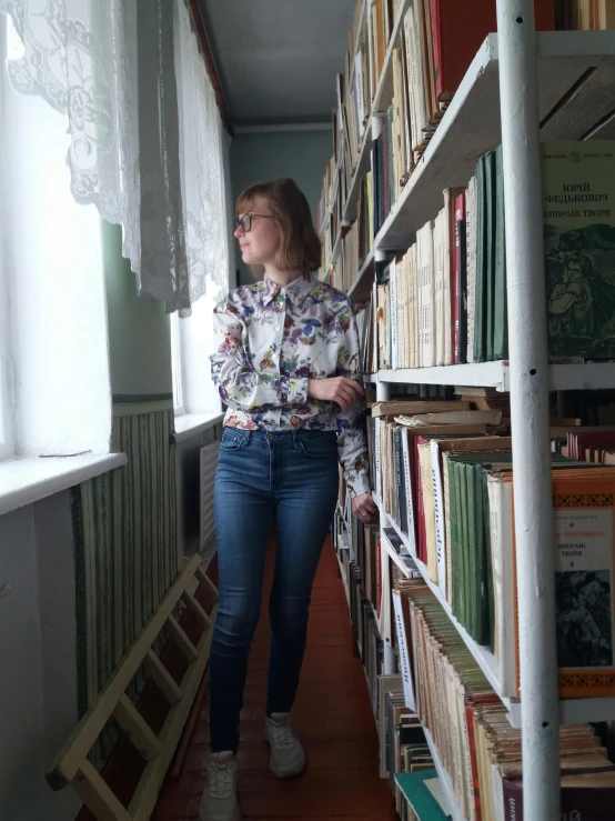 a woman looking down at a bookshelf filled with books
