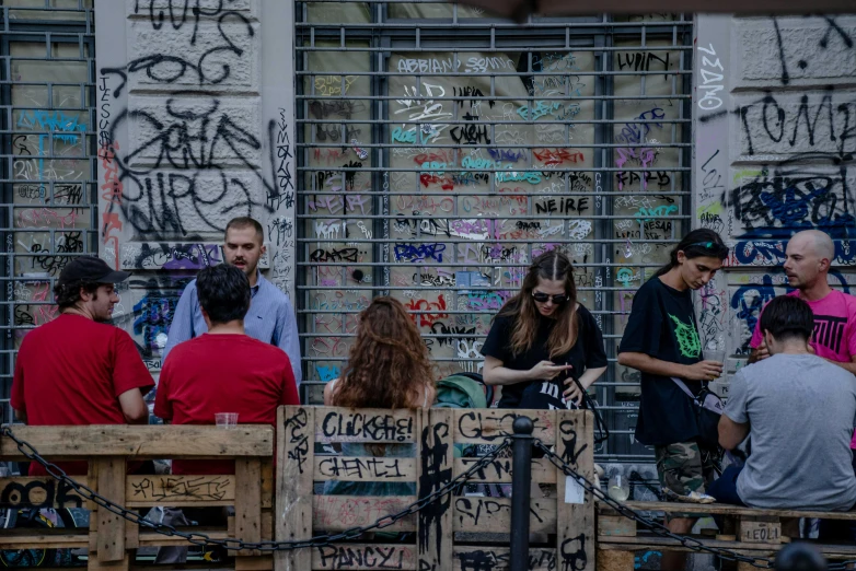 several people sitting down in front of graffiti covered buildings