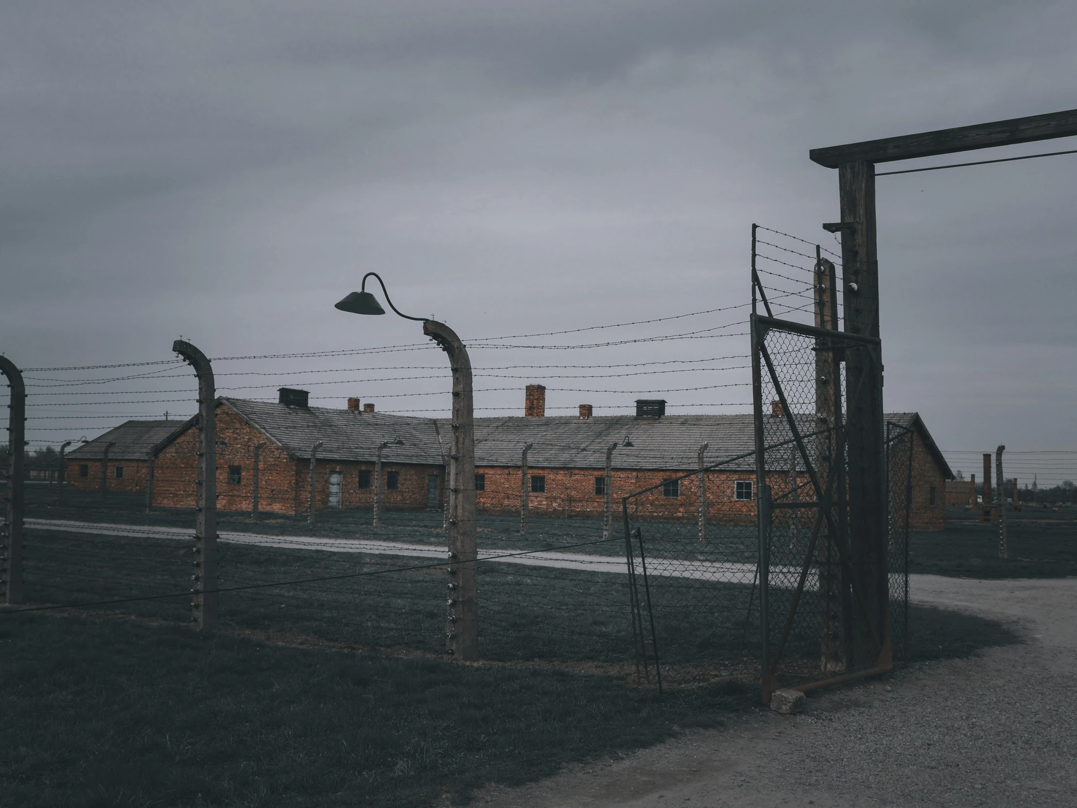 a po of a field and a brick building with a barb wire fence around it