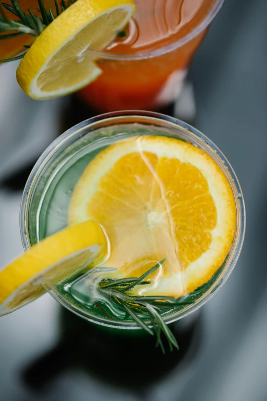 there is a glass filled with lemon and rosemary on the table