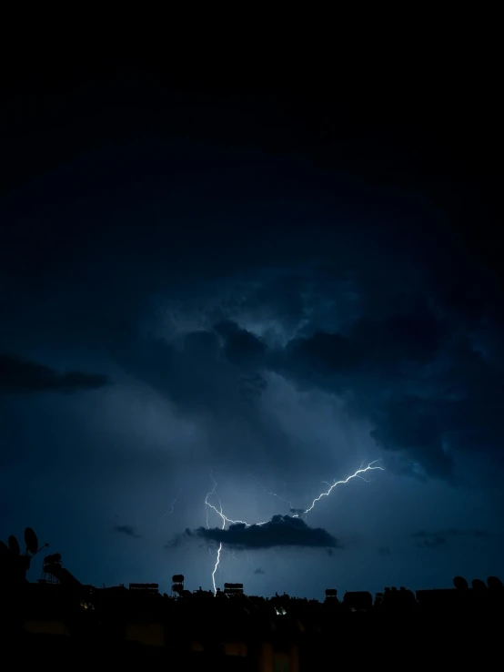 lightning striking over a city at night time