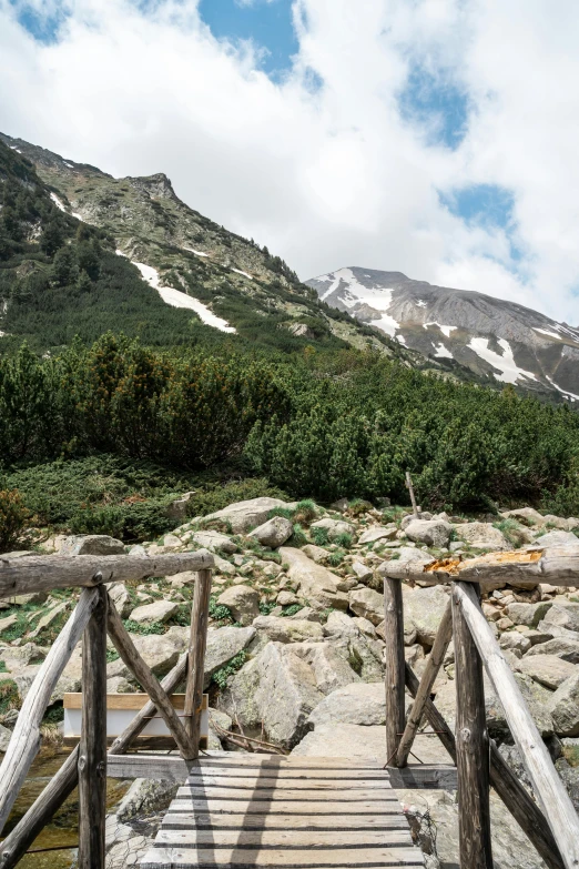 a wooden bridge crosses over some water and rocks