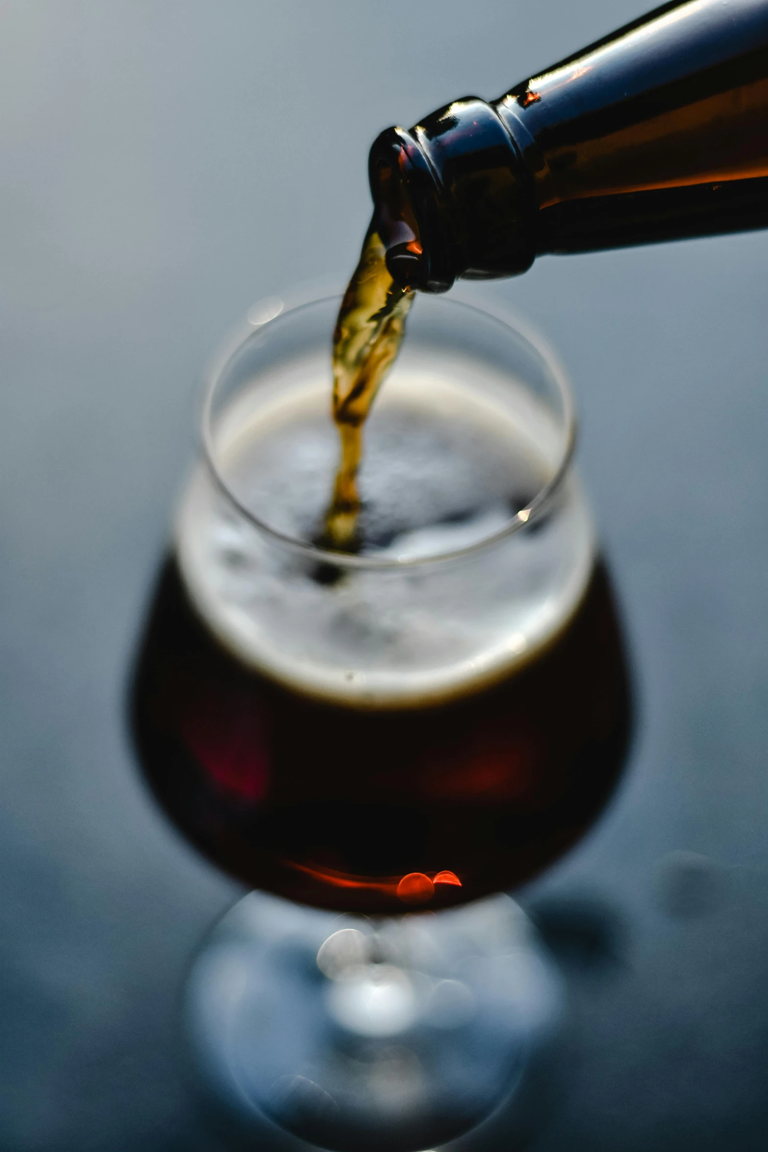 a person pours some beer from a small bottle into a large glass