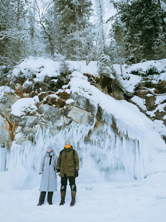 two people in coats stand by a waterfall covered with ice