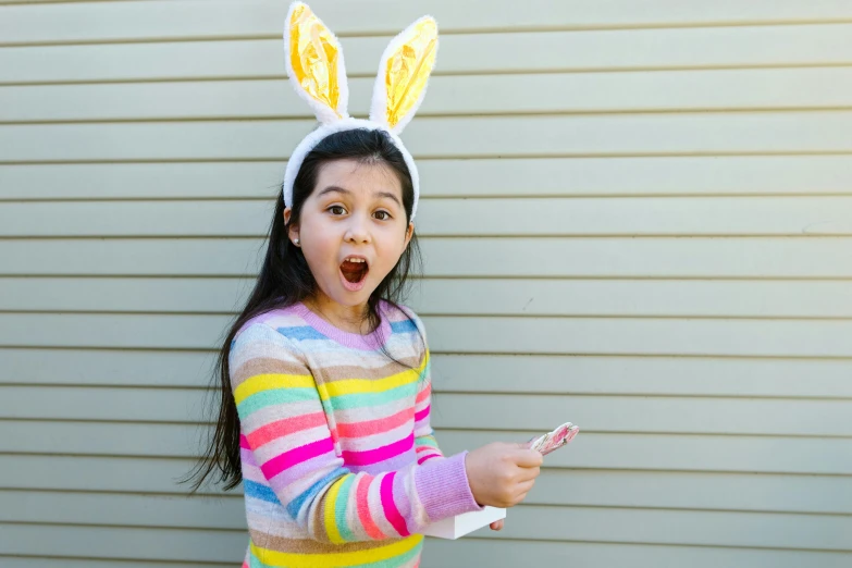 a girl dressed up as an easter bunny pointing at soing