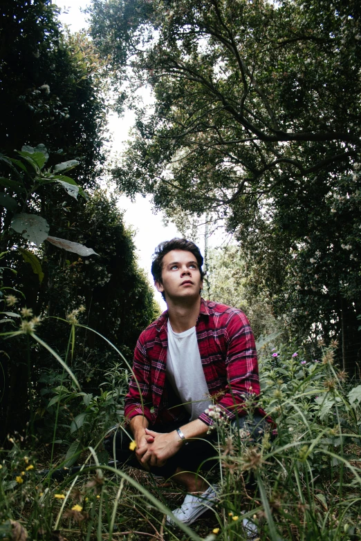 a man kneeling on the ground in tall grass