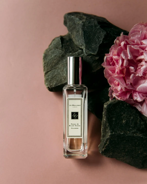 a small bottle of cologne next to pink flowers