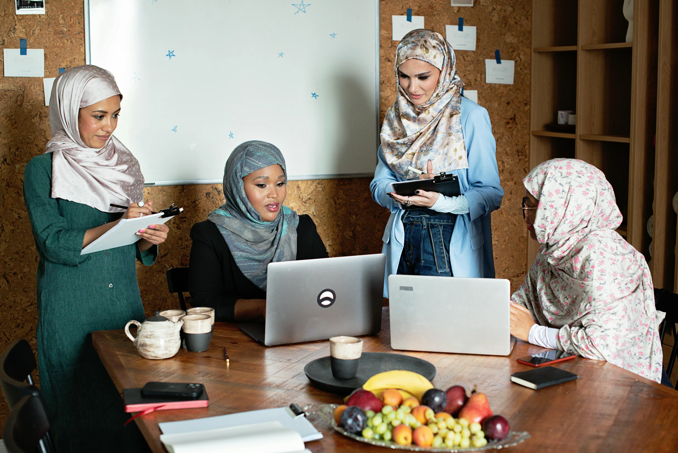 a group of people standing around a laptop on top of a table