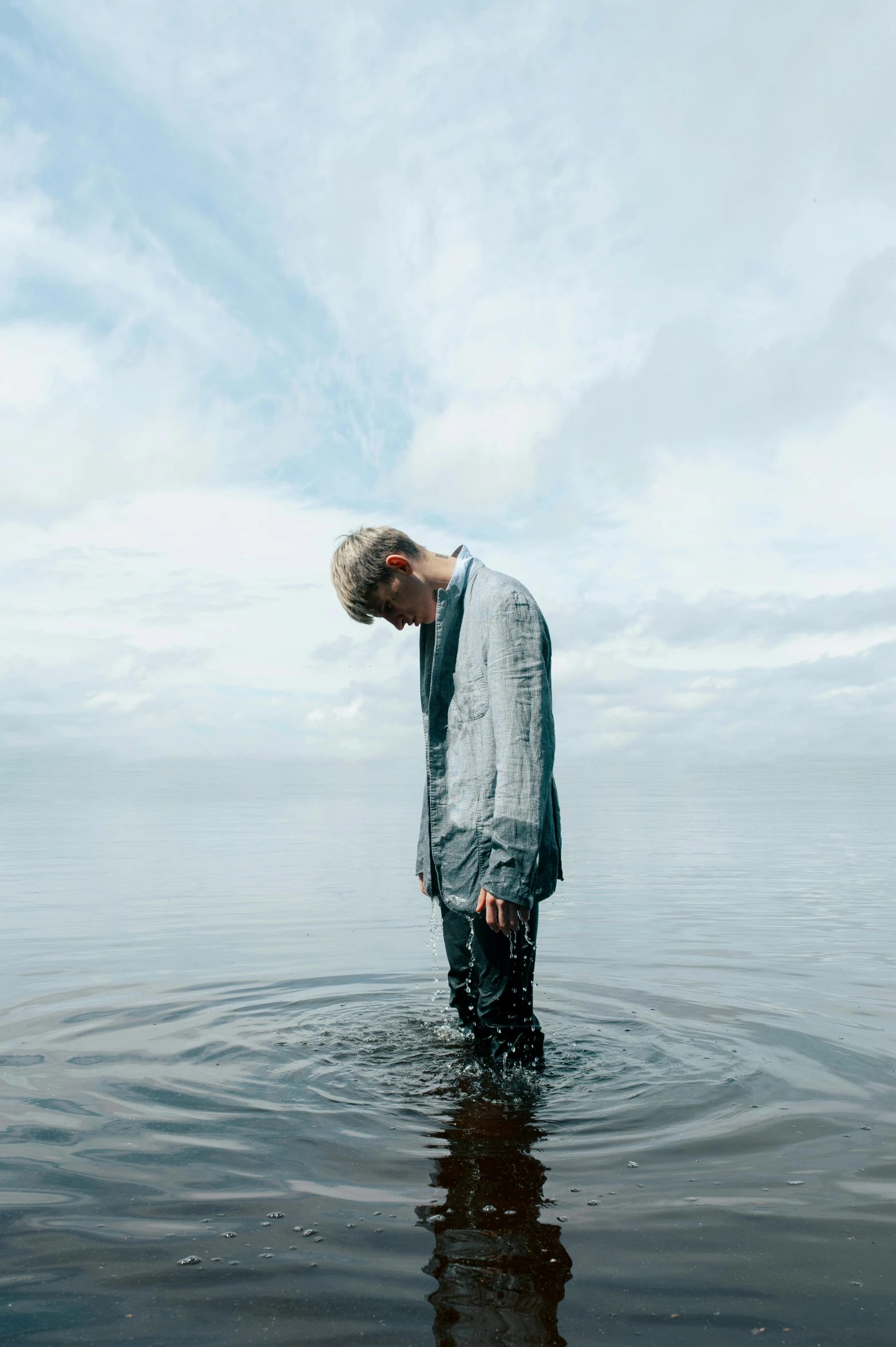 the man is standing in the shallow waters alone