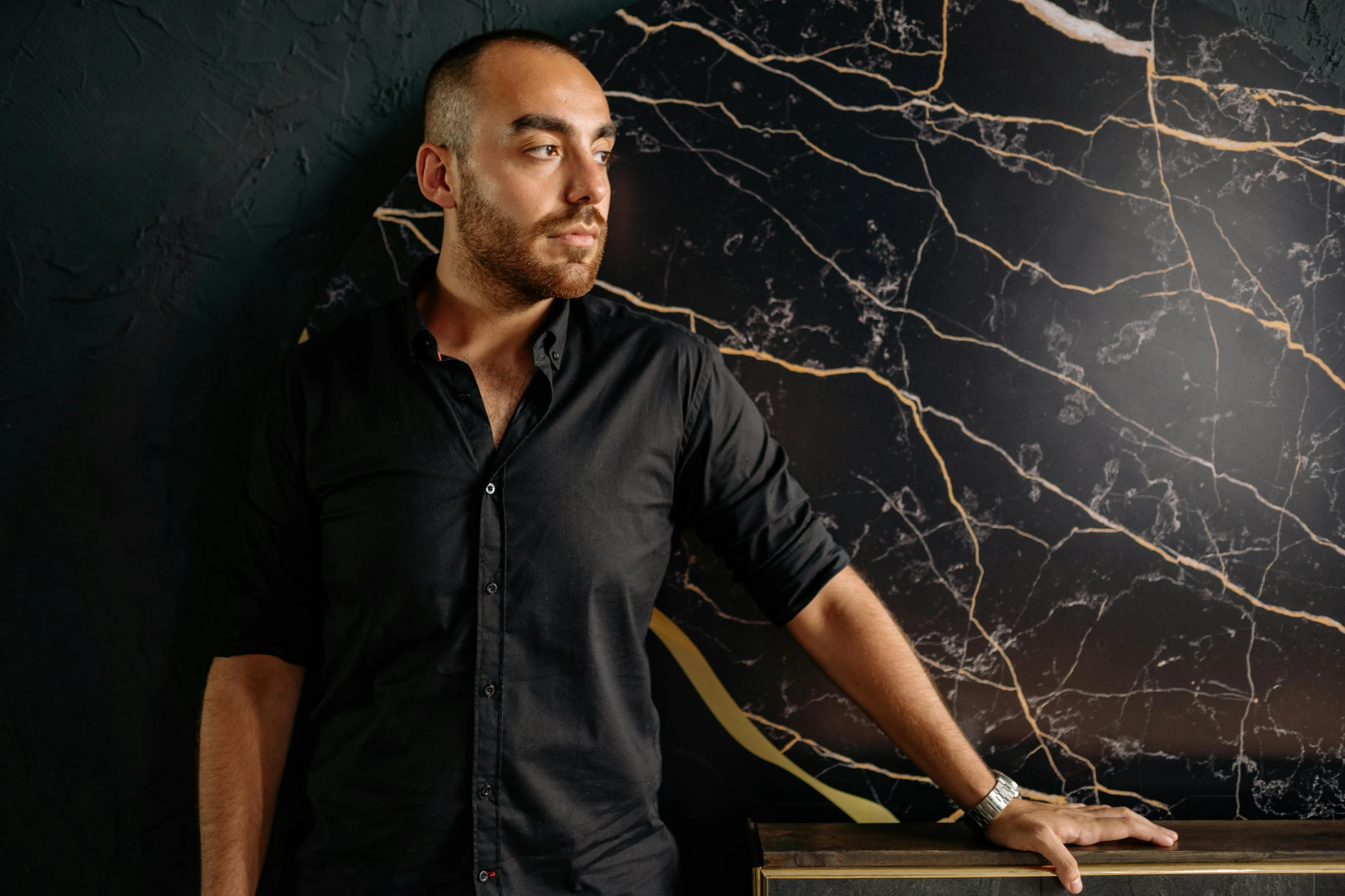 a man leaning on a black marble wall