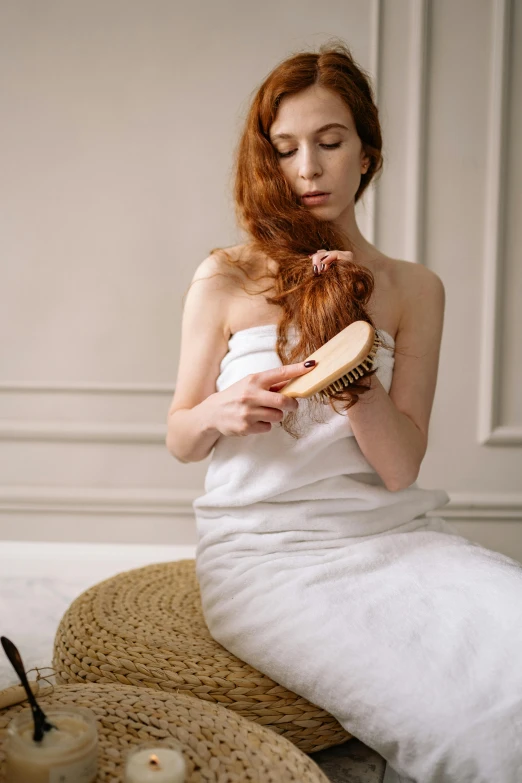 a woman sitting down holding a hair brush