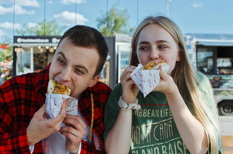 a man and woman eating soing from wrappers