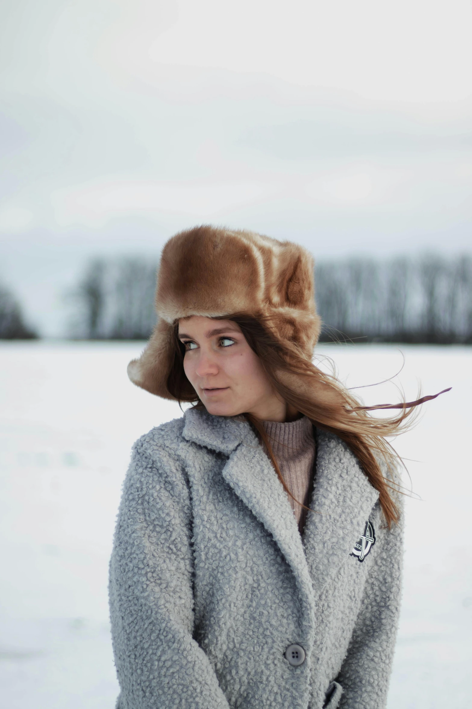 a woman is standing in the snow with a coat and hat on