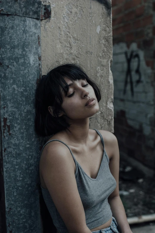 a women with her eyes closed leaning against the wall