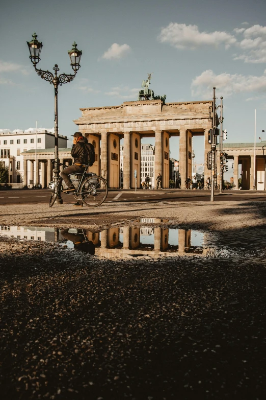 an ancient arch with columns sits in front of a body of water