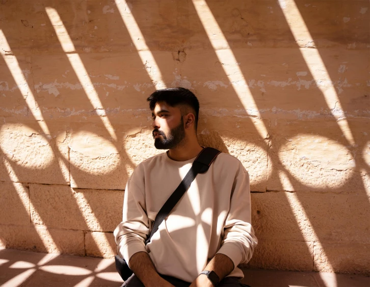 a man sits in front of windows and casts a shadow on a wall