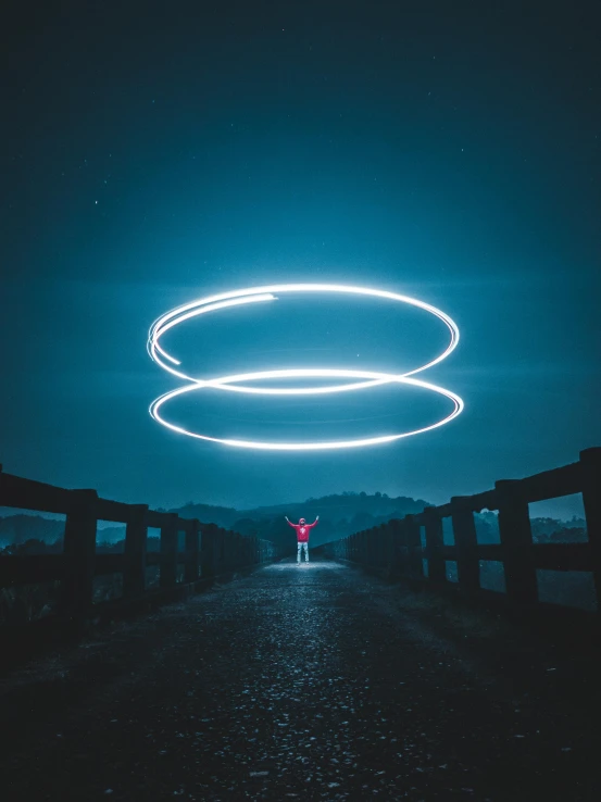 person standing in dark street with arms crossed while circle of light is over them