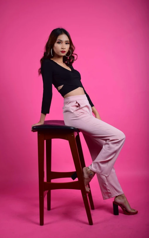 a woman sitting on a chair wearing pink pants