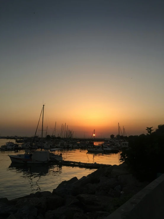 there are many small sailboats at sunset on the water