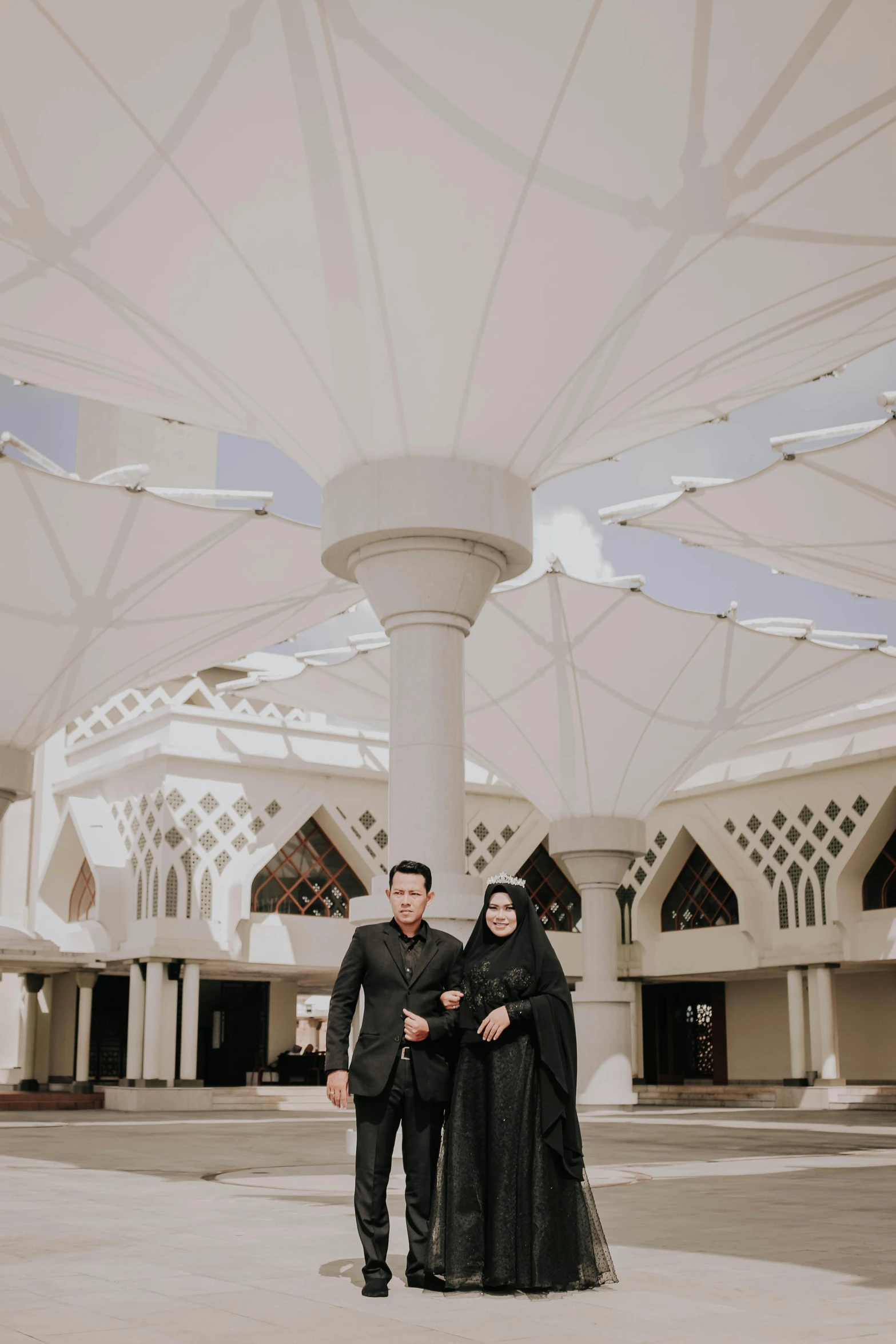 the newly married couple poses beneath an open umbrella