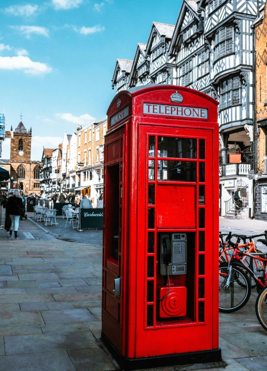 a red telephone booth sitting next to bicycles