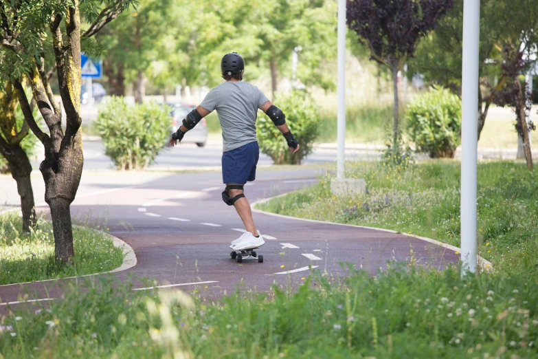 a skateboarder in white shirt on street with trees and road