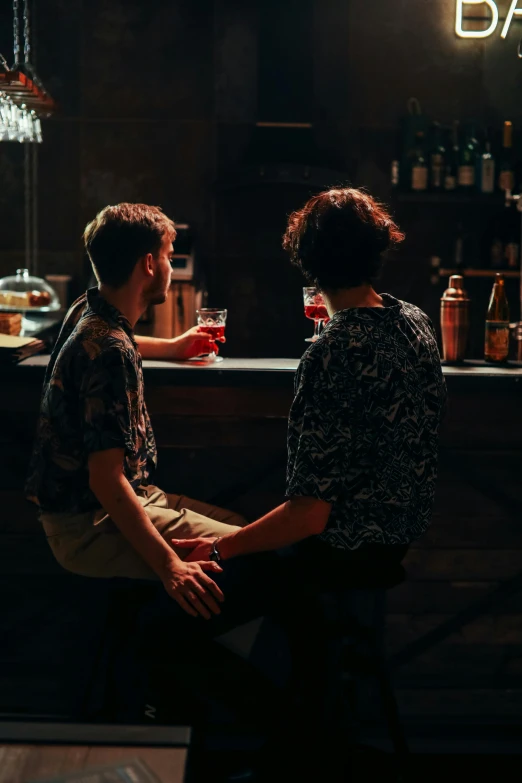 two people sitting at a bar with one drinking soing