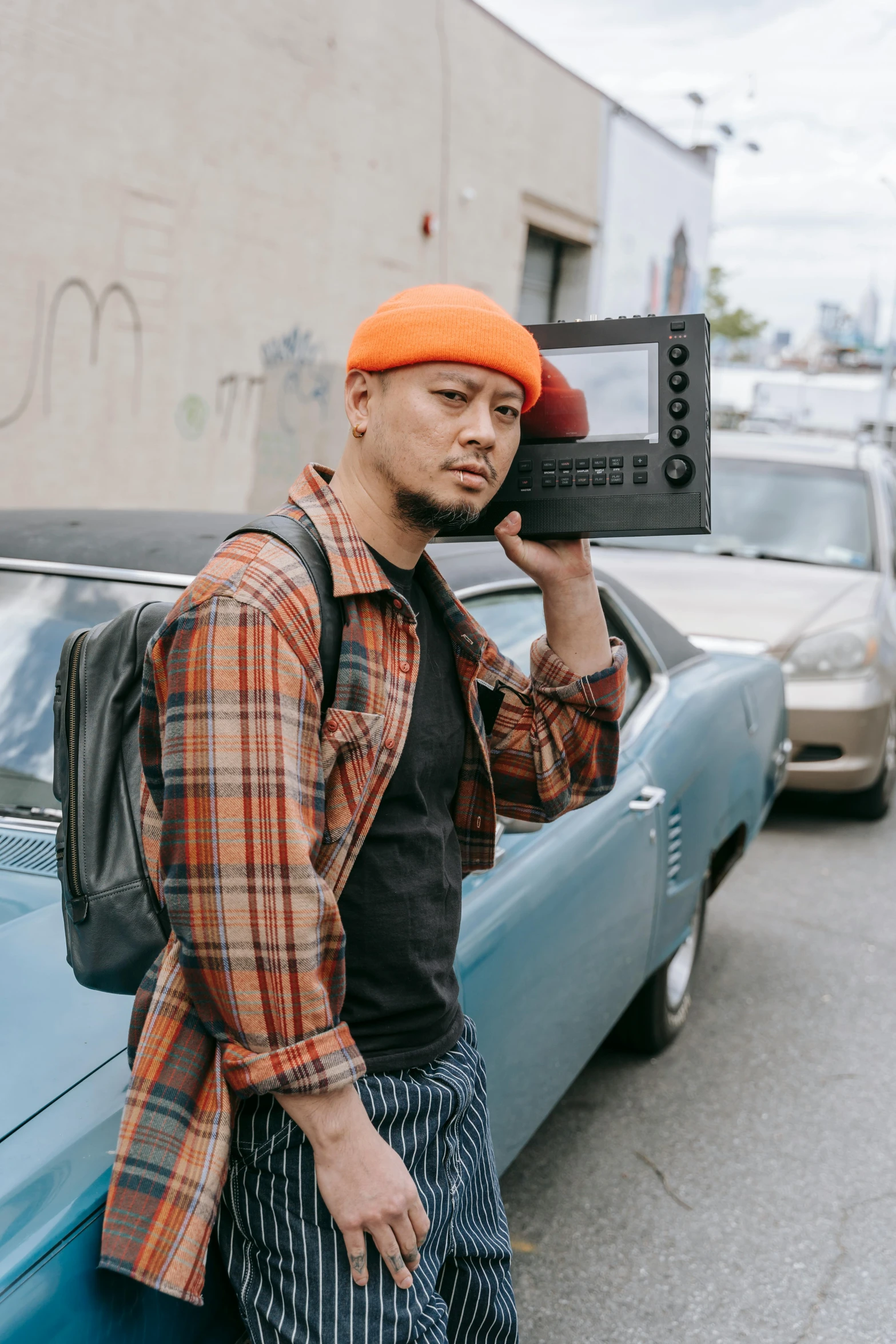 a man leaning against a car holding a camera